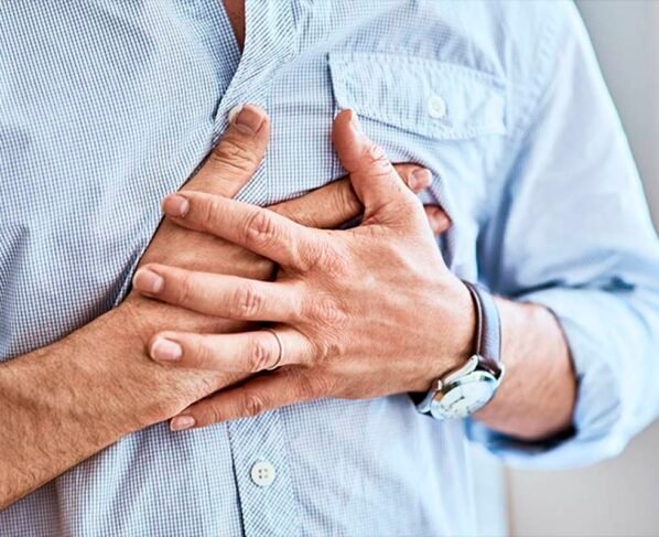 Foto de um homem com camisa azul pressionando o peito - Metrópoles