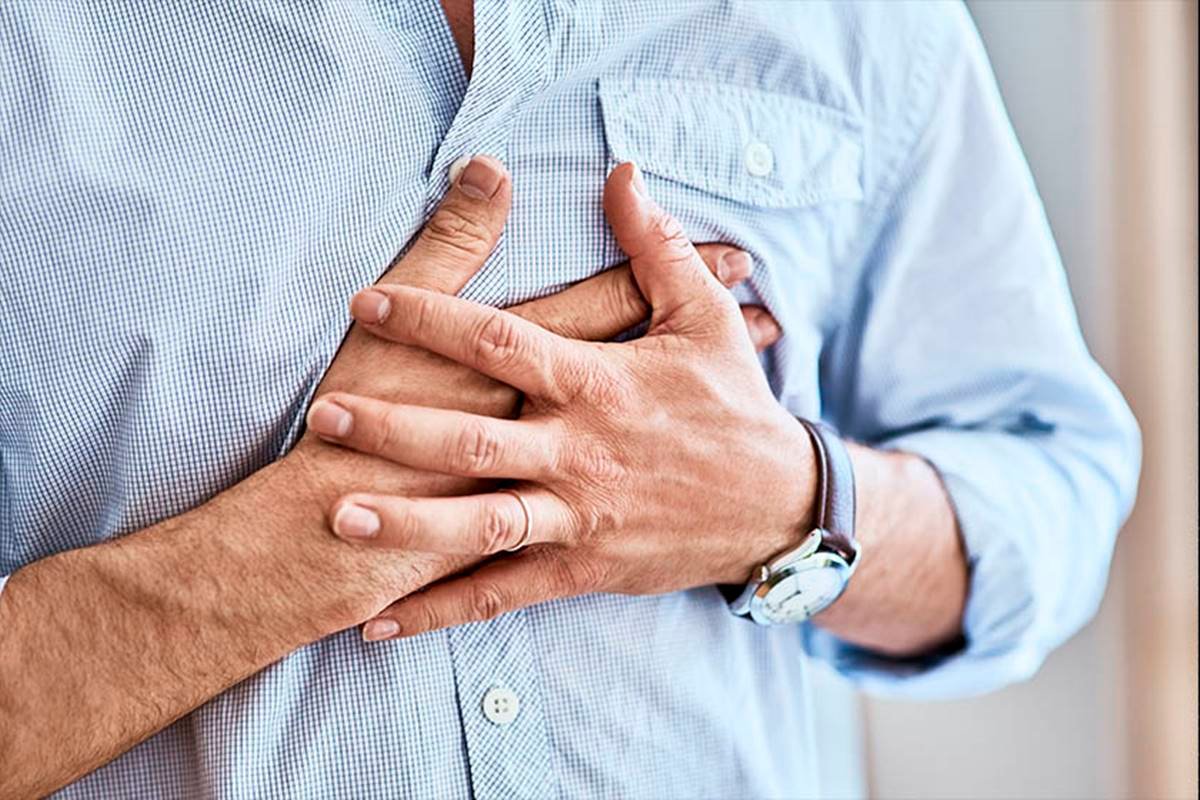 Foto de um homem com camisa azul pressionando o peito - Metrópoles